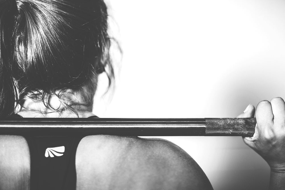 Woman resting barbell on her shoulder.