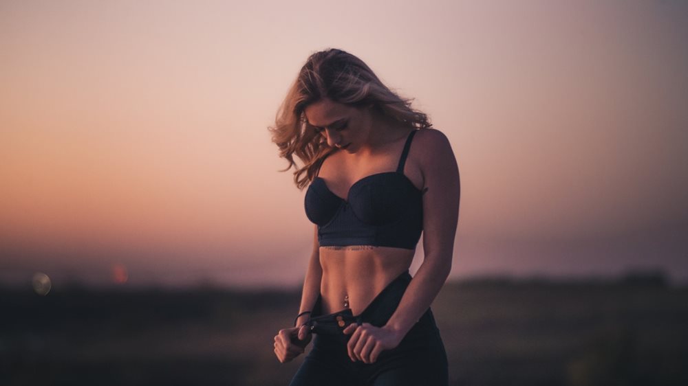 Fit woman posing outdoors at dusk.