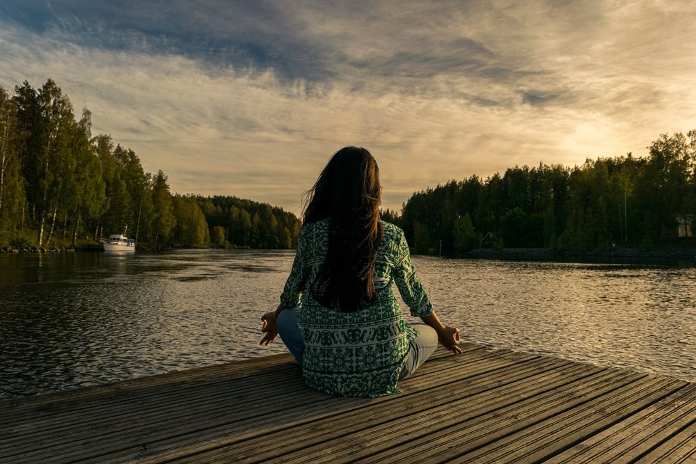 Woman meditating at a lake.