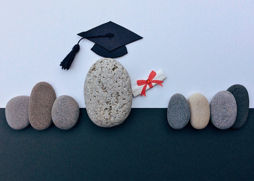 Stones, one with graduation cap and diploma.
