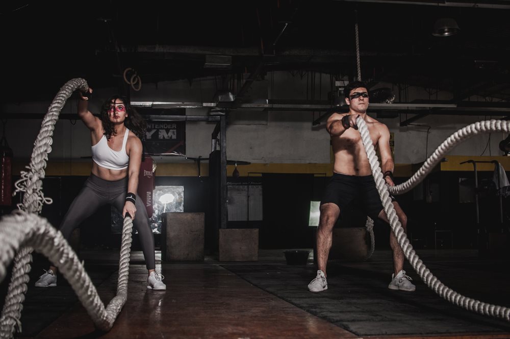 Man and woman, exercising with thick ropes.