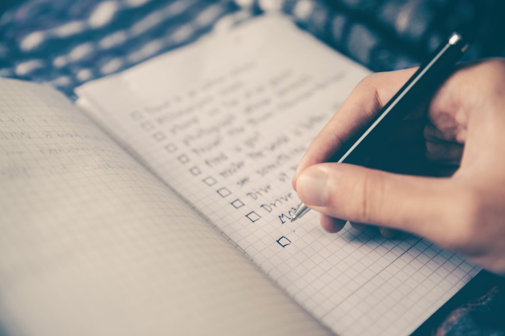 Man creating a checklist in a notebook.