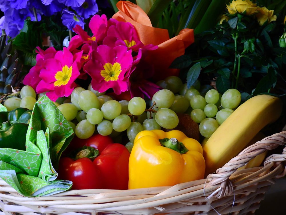 Basket with paprikas, banana, grapes and flowers.