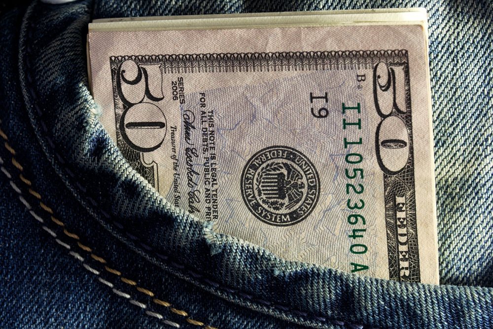 Stack of money bills in jean's pocket.