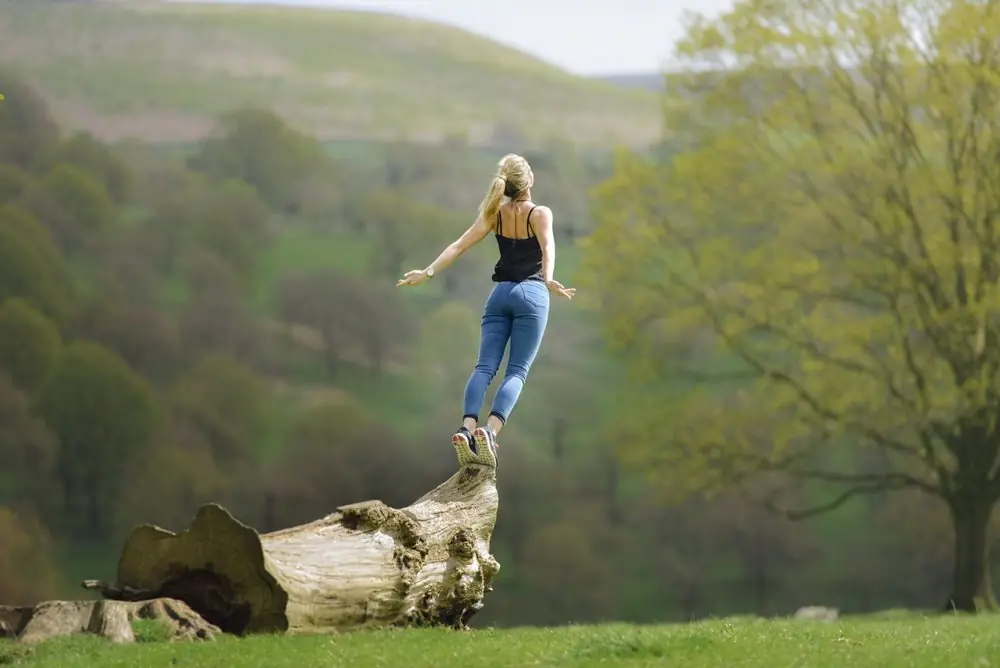 Woman diving off of a pointy log.