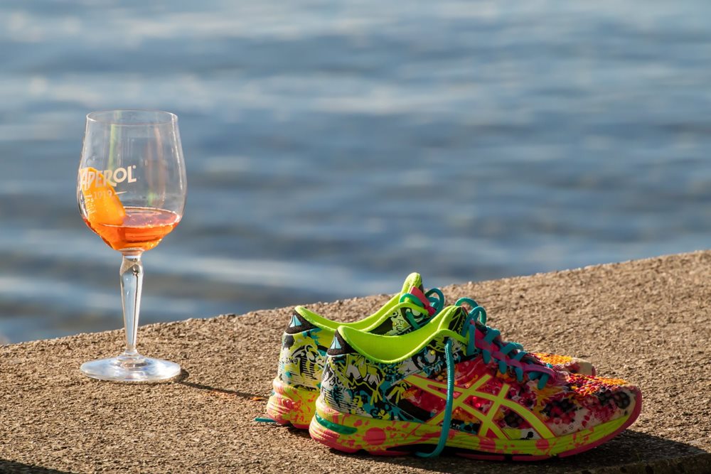 Brightly colored sneakers, next to drink, outdoors.