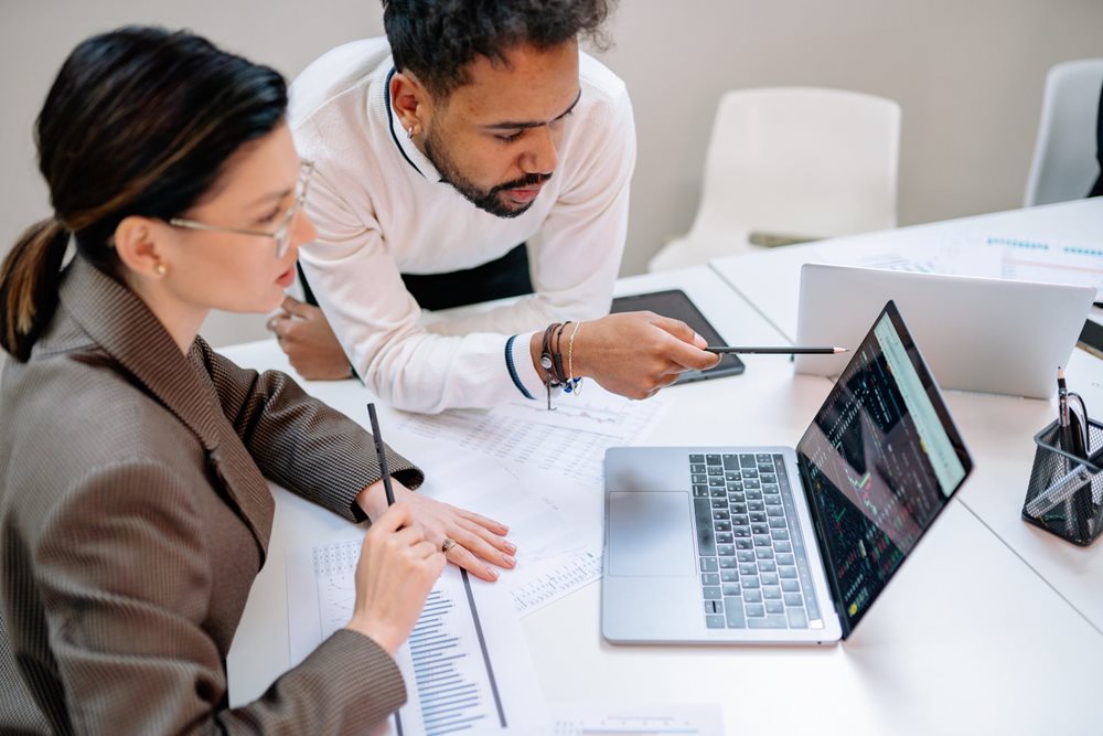 Man and woman studying chart on laptop.