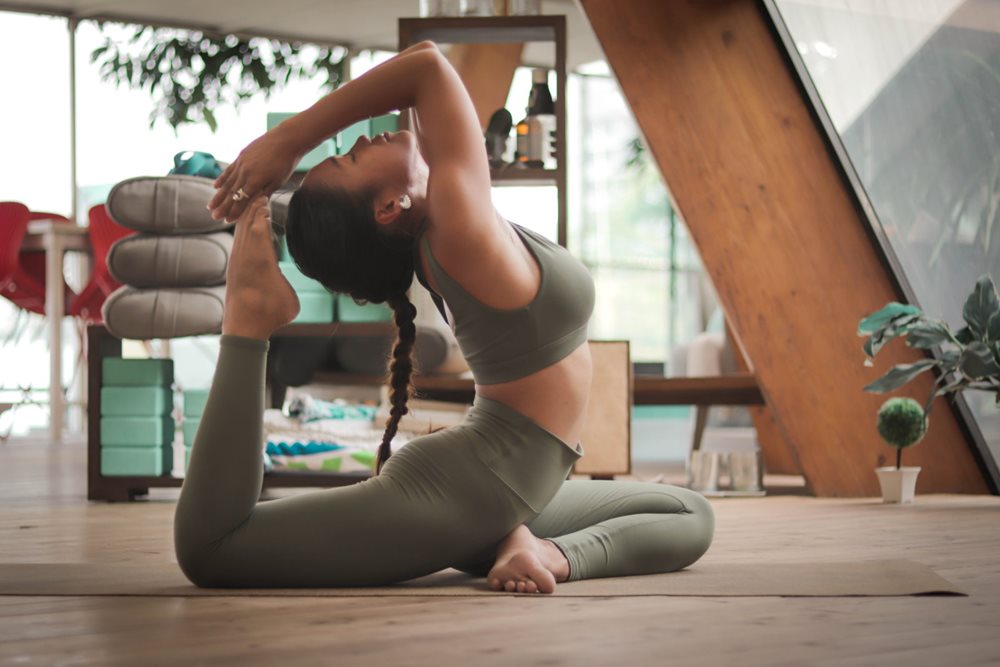 Woman doing yoga, bending leg to back of head.