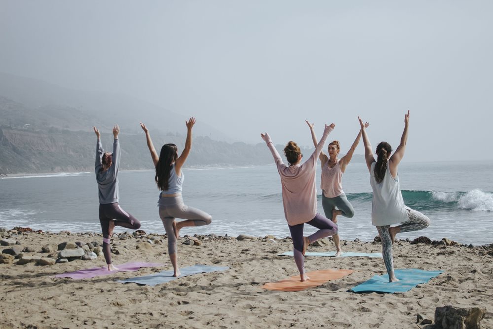 Women doing outdoor yoga at the beach.