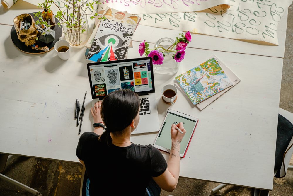 Girl working at desk with laptop and tablet.