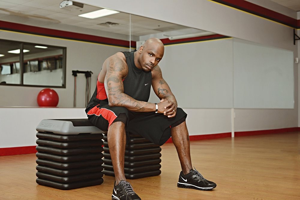 Man in gym, sitting, looking determined.