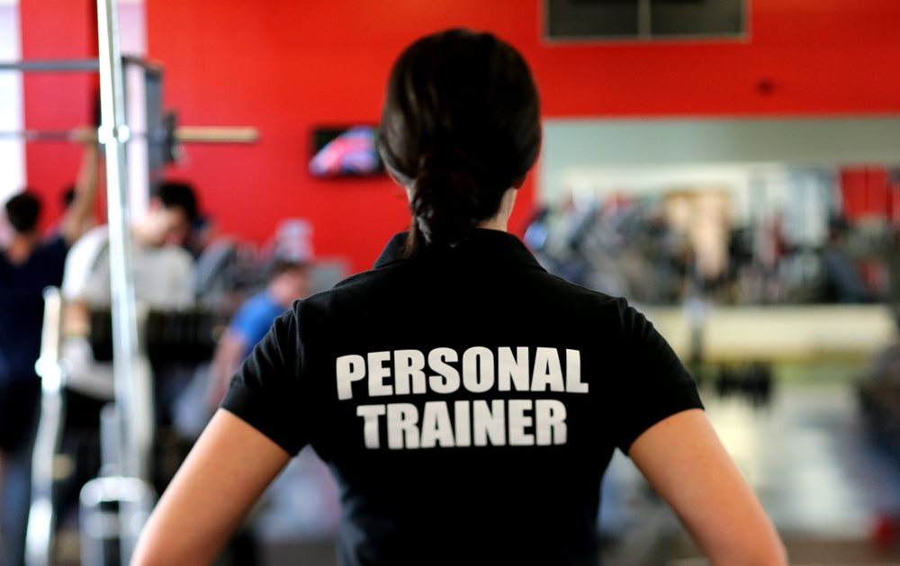 Woman wearing a "personal trainer" shirt, in the gym.