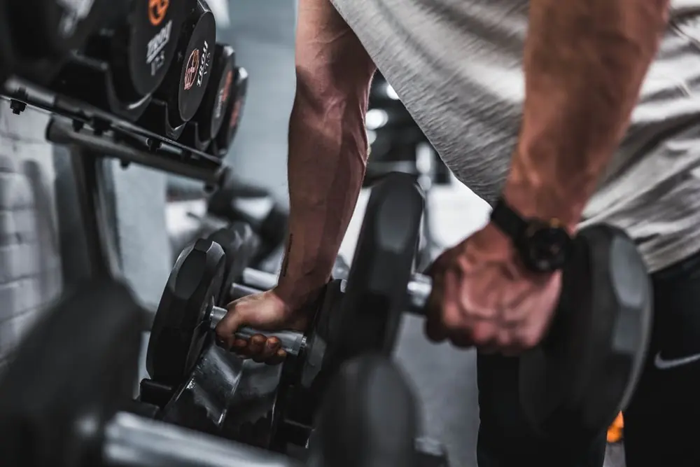 Strong arms picking up dumbbells.
