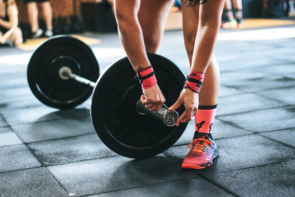 Person adjusting barbell weights.