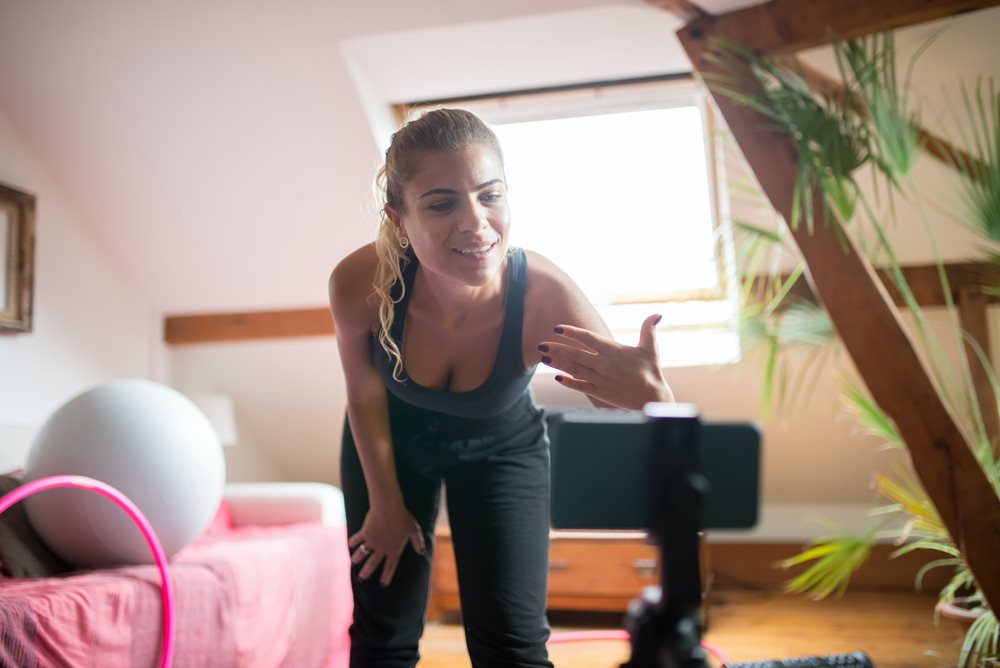 Woman filming virtual fitness session.