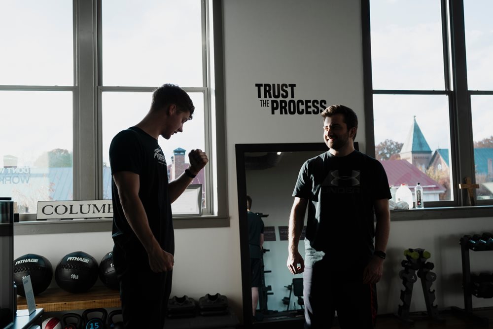 Two guys in gym, talking, smiling.